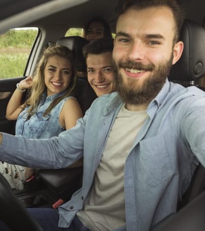 beard-young-man-sitting-with-his-friend-car-taking-selfie